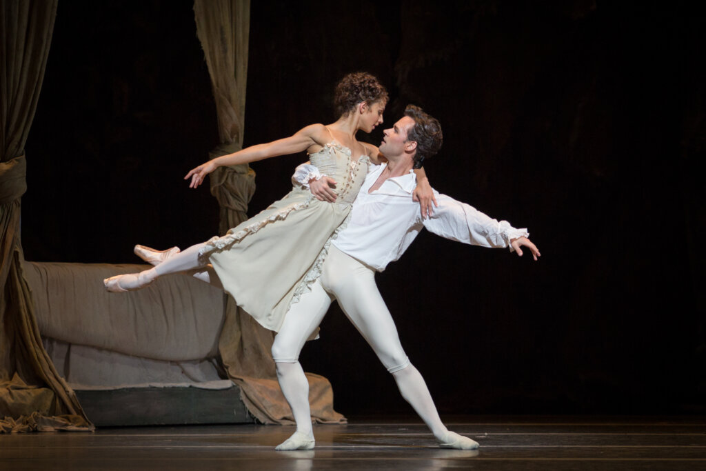 Ballet dancers on the stage - a young woman and man in white in a duet. 